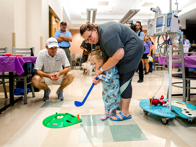 Sanderson Farms Championship golfer Wes Roach gives golfing tips to Children’s of Mississippi patient Ruby Kate Greer and her mom, Kailyn, of Hermanville during a 2019 visit to the children’s hospital.